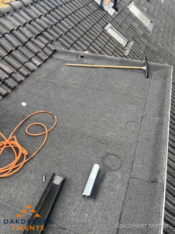 Plat dak reparatie met gereedschap en loodstroken in Twente