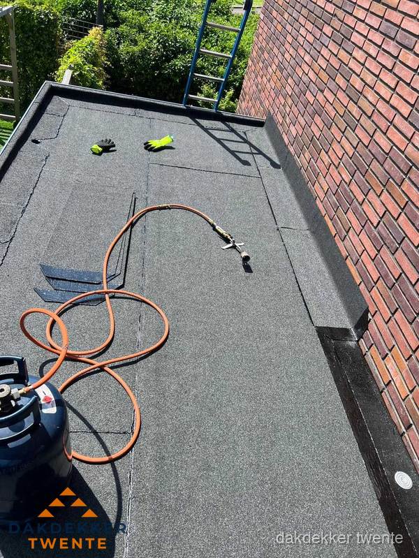 Plat dak met bitumen en brandgereedschap van dakdekkersbedrijf in Twente