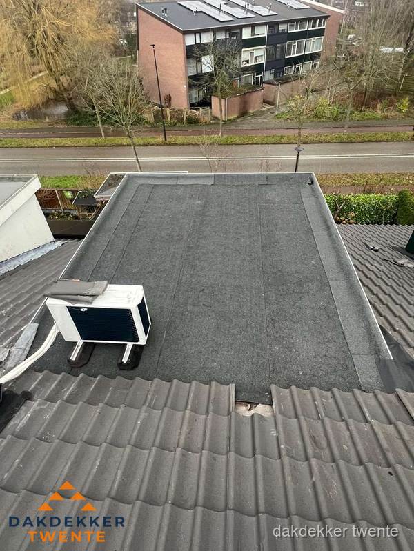 Plat dak inspectie met bitumen bedekking naast schuin pannendak in Twente