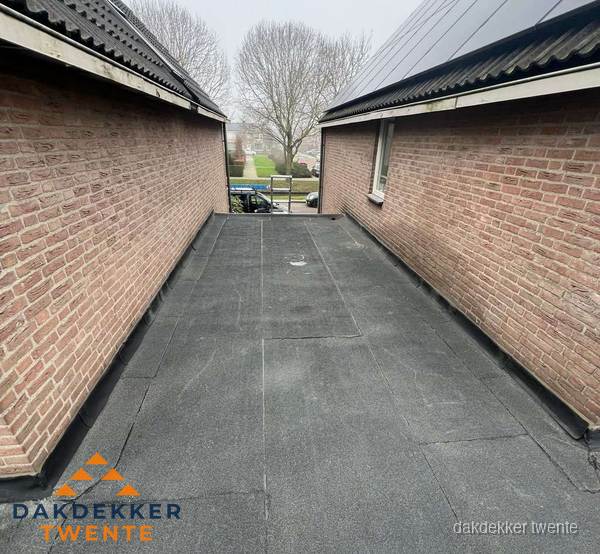 Plat dak met bitumen dakbedekking tussen bakstenen muren in Twente Plat dak met bitumen dakbedekking tussen bakstenen muren in Twente